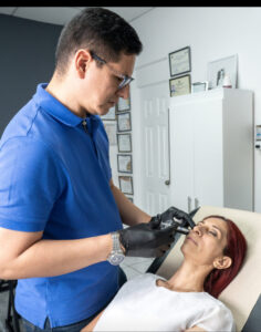Dr. Perdomo aplicando bioestimulador de colágeno en rostro de paciente en consulta, tratamiento de rejuvenecimiento facial de nueva generación en clínica estética Dr. Perdomo