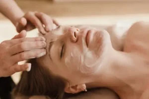 Esteticista aplicando mascarilla limpiadora en rostro de paciente relajada, limpieza facial profunda como base de tratamientos estéticos exitosos en clínica Dr. Perdomo