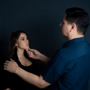 Dr. Perdomo evaluando rostro y mentón de paciente femenina en consulta de medicina estética, análisis previo a tratamiento con toxina botulínica o rellenos dérmicos.