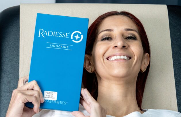 Paciente satisfecha sosteniendo Radiesse antes de su tratamiento de bioestimuladores de colágeno en Clínica Dr. Perdomo