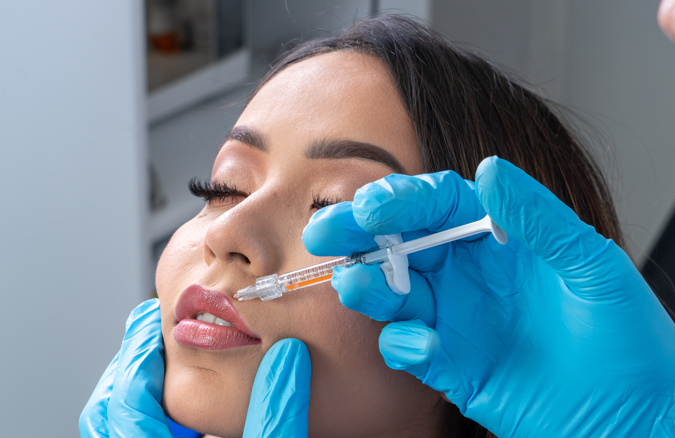 Médico aplicando toxina botulínica en zona nasal de paciente femenina, tratamiento de bótox para afinar y levantar la punta de la nariz en clínica estética Dr. Perdomo