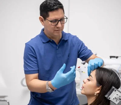Dr. Perdomo aplicando bioestimuladores de colágeno en frente para rejuvenecimiento facial preventivo