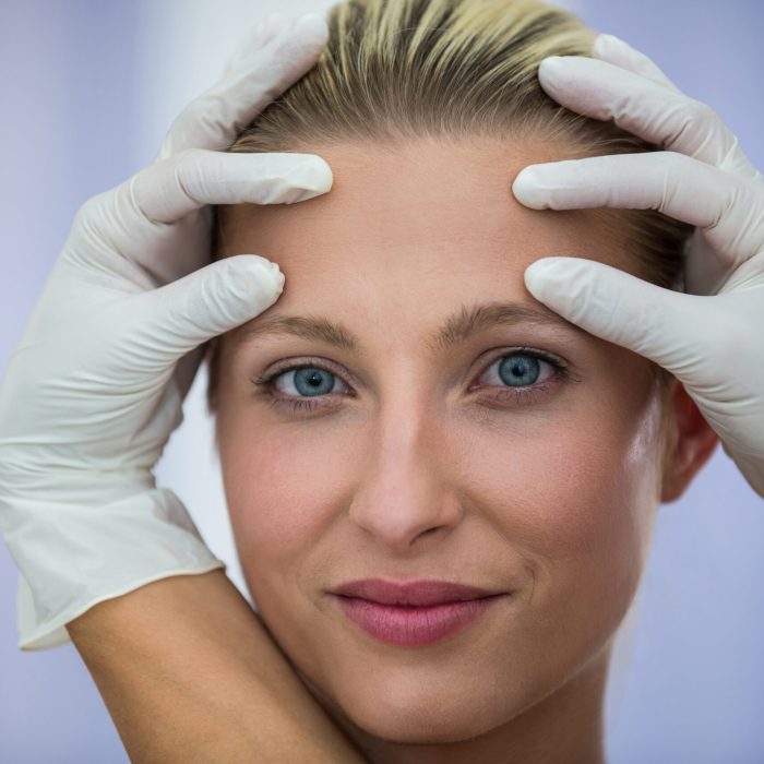 Doctor examining female patients face from cosmetic treatment